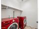 Laundry room features red washer and dryer, and additional shelving for storage at 3850 E Geronimo St, Gilbert, AZ 85295