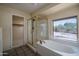 Bright bathroom with a large tub, glass-enclosed shower, and closet access at 6101 E Beck Ln, Scottsdale, AZ 85254