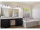 Bright bathroom featuring a large soaking tub, a double vanity, and modern fixtures at 7205 W Fallen Leaf Ln, Peoria, AZ 85383