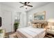 Bright bedroom with a ceiling fan, a cream upholstered bed, and gold accents at 7205 W Fallen Leaf Ln, Peoria, AZ 85383