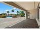 Covered patio featuring a stone paver floor, view of backyard pool, landscaping and palm trees at 7205 W Fallen Leaf Ln, Peoria, AZ 85383