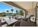 Covered outdoor patio featuring lounge seating, dining area, and a view of the backyard pool and palm trees at 7205 W Fallen Leaf Ln, Peoria, AZ 85383