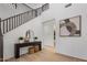 Bright foyer features wood floors, staircase, console table with decorative plants and artwork, and an open hallway to the bathroom at 7616 S Sorrell Ln, Gilbert, AZ 85298
