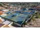 Aerial view of several tennis courts featuring shaded seating, set within a community with mature trees at 906 Leisure World --, Mesa, AZ 85206