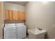 Laundry room has white washer and dryer, wooden cabinets, and utility sink at 12642 N Mountainside Dr # D, Fountain Hills, AZ 85268