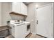 Well-lit laundry room includes modern washer and dryer with plenty of cabinet storage at 14161 W Poinsettia Dr, Surprise, AZ 85379