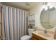 Bright bathroom featuring a round mirror and a white vanity with a sink and a striped shower curtain at 1454 W Capri Ave, Mesa, AZ 85202