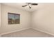 A neutral toned bedroom is carpeted and has a window with wood-tone blinds and a ceiling fan at 17419 W Elaine Dr, Goodyear, AZ 85338