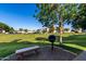 A charcoal grill and stone bench sit in a grassy common area between apartment buildings on a sunny day at 1941 S Pierpont Dr # 1037, Mesa, AZ 85206