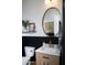 A modern half-bathroom features wood-look vanity, gold accents, and contrasting black-and-white wainscoting at 26885 N 104Th Pl, Scottsdale, AZ 85262
