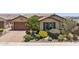 Tan single-story home with a brown garage door, desert landscaping, and colorful bushes in front at 33305 N 26Th Ave, Phoenix, AZ 85085