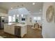 Open-concept kitchen with stainless steel appliances, white cabinetry, and an island, seamlessly flowing into the dining and living areas at 40927 W Sunland Dr, Maricopa, AZ 85138