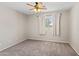 Neutral bedroom featuring a ceiling fan and window with white curtains at 4154 W Morten Ave, Phoenix, AZ 85051