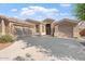 Tan home exterior showcasing a well-maintained yard, a three-car garage, and a welcoming entrance under a sunny sky at 4667 E County Down Dr, Chandler, AZ 85249