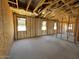 Unfinished living room features exposed framing, insulation, and multiple window placements at 46868 W Coe St, Maricopa, AZ 85139