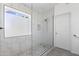 Modern glass-enclosed shower with marble tile and pebble flooring at 5211 W Wikieup Ln, Glendale, AZ 85308