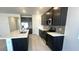 View of kitchen with dark cabinets, stainless steel appliances, large island with white countertop, and wood-look tile floors at 5645 S 253Rd Ave, Buckeye, AZ 85326