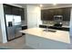 This modern kitchen features dark cabinetry, stainless steel appliances, and a large island with a white countertop at 5645 S 253Rd Ave, Buckeye, AZ 85326
