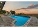 An inviting pool with stone coping and pavers overlooks a stunning desert landscape at sunset at 6432 E El Sendero Rd, Carefree, AZ 85377