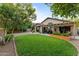 Beautiful backyard with a well-maintained lawn, mature trees, and a covered patio for outdoor entertaining at 6907 W Monona Dr, Glendale, AZ 85308