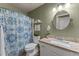 Inviting bathroom features blue and white shower curtain, granite countertops and a round mirror above the sink at 6907 W Monona Dr, Glendale, AZ 85308