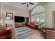 Cozy living room featuring leather sofas, ceiling fan, and large window with shutters at 6907 W Monona Dr, Glendale, AZ 85308