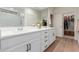 Elegant bathroom featuring double sinks, white cabinets, quartz countertop, and a walk-in closet at 7123 W Andrea Dr, Peoria, AZ 85383