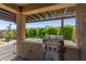 Covered patio with a built in stainless steel grill overlooking the backyard and mature landscaping at 7123 W Andrea Dr, Peoria, AZ 85383