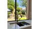 Backyard views from kitchen sink including putting green, patio, and landscaped yard at 7128 E Bramble Berry Ln, Scottsdale, AZ 85266