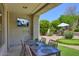 Relax and entertain on the covered patio with a TV, dining table, and view of the backyard putting green at 7128 E Bramble Berry Ln, Scottsdale, AZ 85266