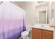 Well-lit bathroom featuring vanity, mirror, toilet, and a purple shower curtain at 8132 E Onza Ave, Mesa, AZ 85212