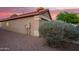 Side view of a home featuring stucco siding, a red tile roof, and desert landscaping against a vibrant twilight backdrop at 8132 E Onza Ave, Mesa, AZ 85212