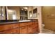 Bathroom vanity features rich wood cabinetry, granite countertop, and double mirrors at 9505 E Jenan Dr, Scottsdale, AZ 85260