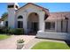 Stunning home exterior with arched entryway and manicured front lawn at 9505 E Jenan Dr, Scottsdale, AZ 85260