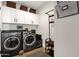 Well-organized laundry room with modern appliances, storage cabinets, and open shelving at 9821 E Windrose Dr, Scottsdale, AZ 85260
