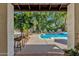 Outdoor seating by the pool with a built-in grill and bar, perfect for entertaining at 9821 E Windrose Dr, Scottsdale, AZ 85260