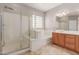 Bright bathroom features a shower, soaking tub, wood cabinets, decorative window and tile flooring at 13617 W Crocus Dr, Surprise, AZ 85379