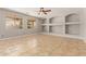 Bright living room featuring tile floors, lots of natural light, and custom built-in shelving at 13617 W Crocus Dr, Surprise, AZ 85379