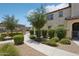 A trimmed green hedge runs beside the walking path along the side of the home at 14870 W Encanto Blvd # 1091, Goodyear, AZ 85395