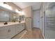 Bathroom featuring a dual sink vanity with white cabinetry and a glass shower at 17597 W Red Fox Rd, Surprise, AZ 85387