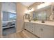 Bright bathroom featuring a dual sink vanity with white cabinetry and a large mirror at 17597 W Red Fox Rd, Surprise, AZ 85387