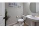 Charming half-bathroom featuring a pedestal sink, decorative wall art, and wood-look tile flooring at 17597 W Red Fox Rd, Surprise, AZ 85387