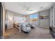 Bright bedroom featuring neutral tones, plush carpeting, a ceiling fan, and a window with neighborhood views at 17597 W Red Fox Rd, Surprise, AZ 85387