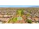 Aerial view of a community park featuring a green field, a basketball court, and walking paths at 17597 W Red Fox Rd, Surprise, AZ 85387