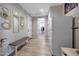 Hallway with wood floors, decorative mirrors, a bench, and a white refrigerator with a view to a closet at 17597 W Red Fox Rd, Surprise, AZ 85387