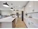 Bright kitchen features modern white cabinetry, quartz countertops, stainless steel appliances, and wood-look tile flooring at 17597 W Red Fox Rd, Surprise, AZ 85387