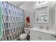 A well-lit bathroom featuring a shower-tub combo, vanity, mirrored medicine cabinet, and blue patterned shower curtain at 18132 W Cardinal Dr, Goodyear, AZ 85338