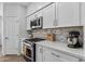 Charming kitchen with white cabinets, stainless steel appliances, mosaic tile backsplash, and wood laminate flooring at 18132 W Cardinal Dr, Goodyear, AZ 85338