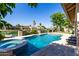 Backyard view featuring a luxurious pool, a spa, palm trees, and waterfront homes at 1834 E Willow Tree Ct, Gilbert, AZ 85234