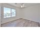 Sunlit bedroom with wood-look floors, ceiling fan, and a large window with neighborhood views at 21141 N 79Th Ave, Peoria, AZ 85382